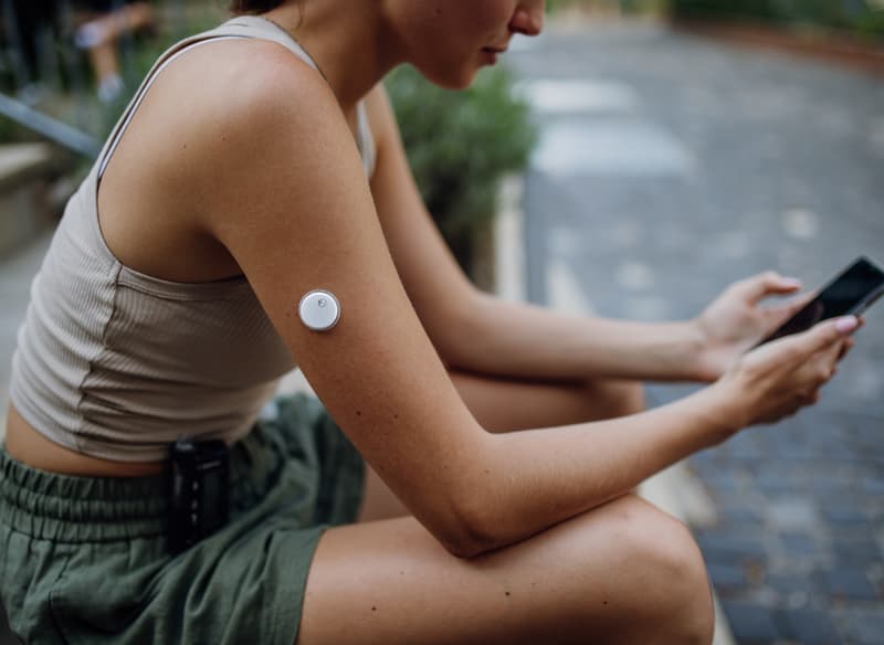 A woman with a sensor on her upper arm using her phone