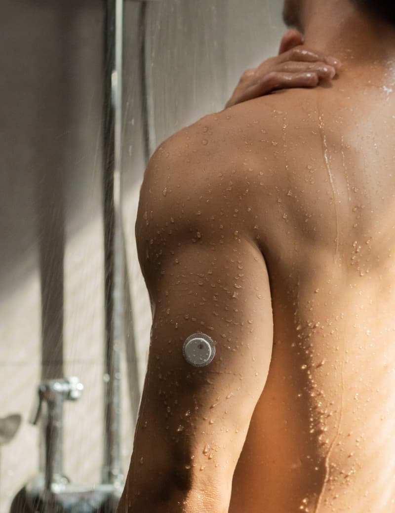 A person showering while wearing a sensor on the upper arm