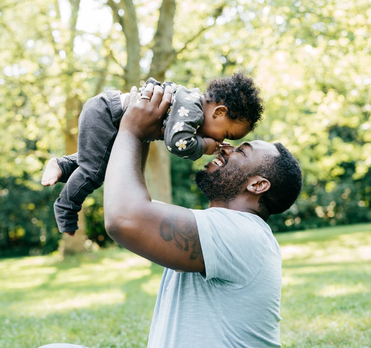 A father lifting his smiling child in a sunny park
