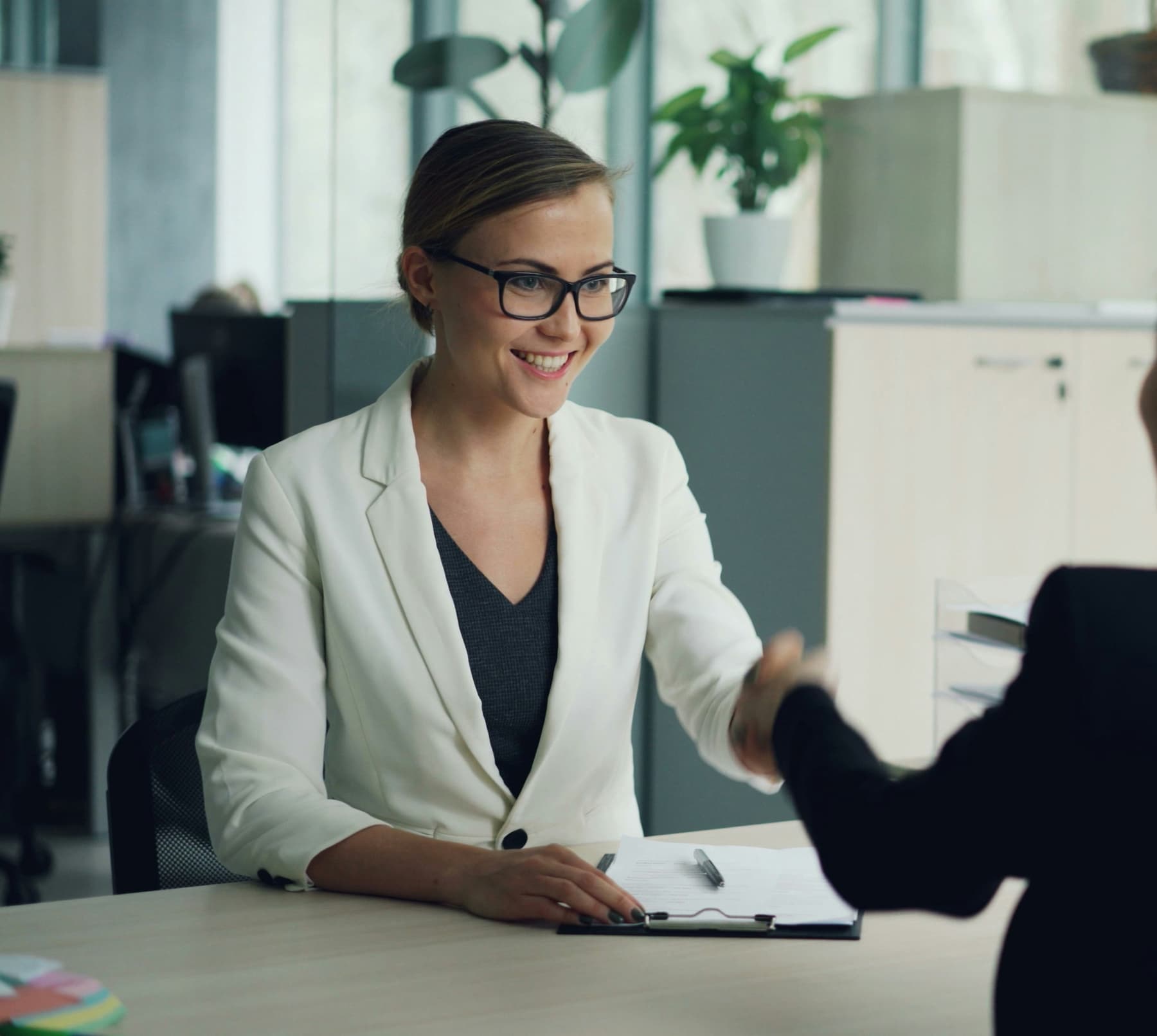 Two professionals shaking hands across a desk