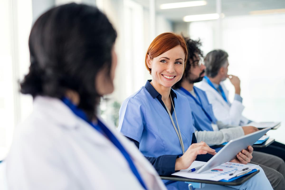 A healthcare trainer working with a tablet beside colleagues